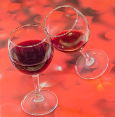 Glasses with red wine, red hearts background