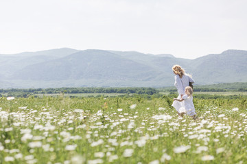 Happy mother playing with her daughter in flower field