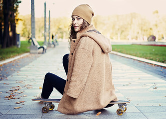 Fashion young woman sitting on a longboard