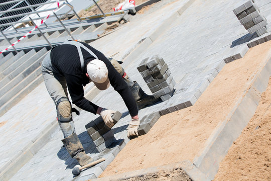 construction worker installing paver bricks during roadworks