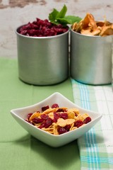 Cornflakes with red berries in a bowl on green cloth