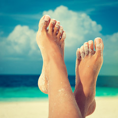 Tanned well-groomed feet amid tropical turquoise sea

