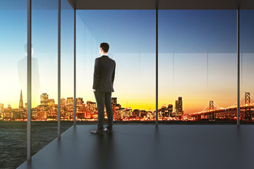businessman in the office looking over the city at sunset