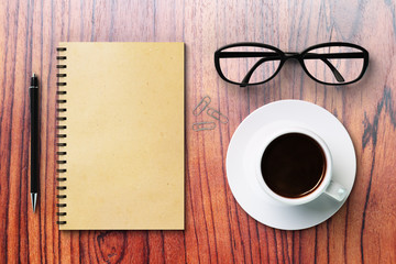 Blank diary and coffee cup on a wooden surface