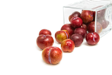 Sweet plums in glass jar on white background