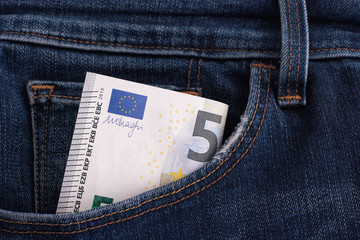 Five euro banknote in a pocket of blue jeans