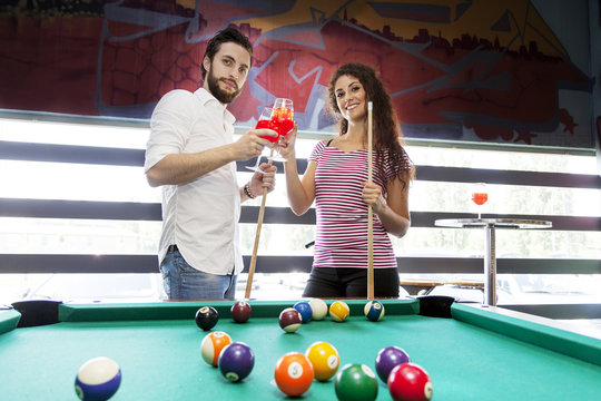 happy couple toast after a game of billiards