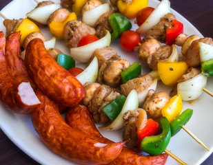Fresh skewers and sausage on a plate ready on the barbecue.