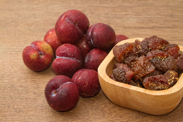 Dried plums and fresh plums on the wooden table