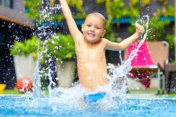 excited happy kid boy jumping in pool, water fun © Olesia Bilkei
