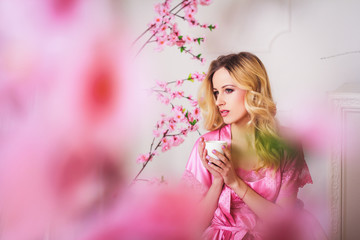 Obraz na płótnie Canvas Blond beautiful woman in pink dressing gown
