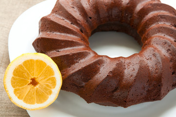 Chocolate honey cake and half of lemon on white plate close up