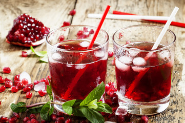Fresh red juice cocktail with pomegranate seeds, mint and ice, s