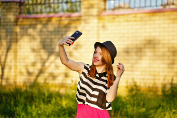 Lovely girl in a hat on the street makes Selfei