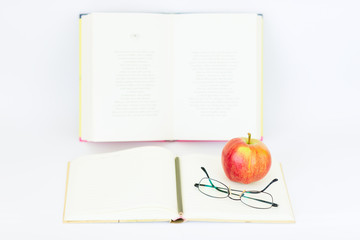Open blank notebook with glasses, apple, and pencil on the top
