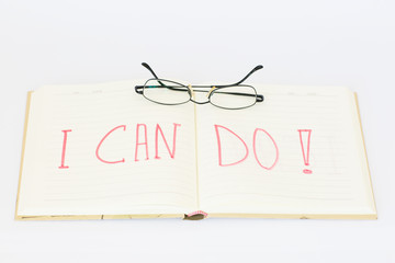 Open notebook with text "I can do!", and glasses on the top