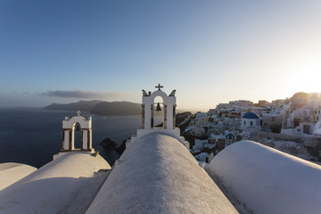 White Greek Orthodox churches on the cliff in Oia (Ia) at sunset, Santorini island, Cyclades Greece