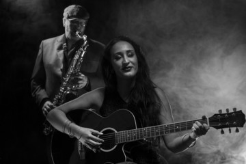 Obraz premium Lady guitarist with a saxophonist
