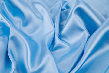 Soft folds of blue silk cloth texture.