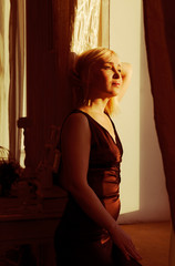 Fototapeta premium Portrait of a woman by the window in sunlight