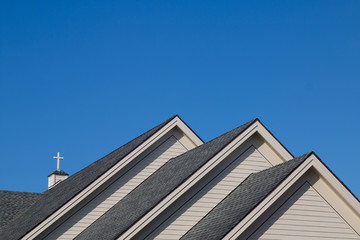 Church roof with cross against blue sky.