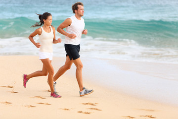 Running couple jogging on beach exercising sport