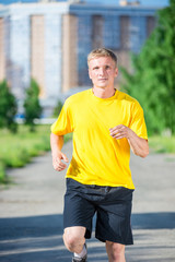 Sporty man jogging in city street park. Outdoor fitness.