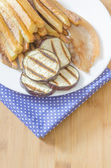 Fries potatoes with grilled eggplant on wooden background