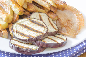 Fries potatoes with grilled eggplant on wooden background