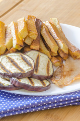 Fries potatoes with grilled eggplant on wooden background