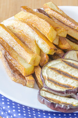 Fries potatoes with grilled eggplant on wooden background