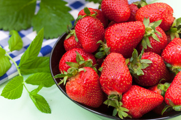 Black bowl filled with  juicy  ripe red strawberries 