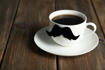White cup with paper mustache on brown wooden background