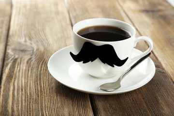 White cup with paper mustache on brown wooden background