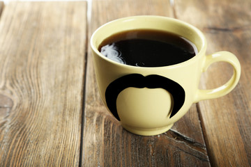 Yellow cup with paper mustache and coffee 