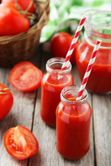 Fototapeta na wymiar Fresh red tomatoes in basket and juice in bottles