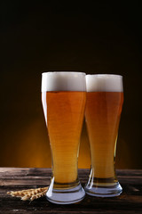 Two glass of beer on brown wooden background