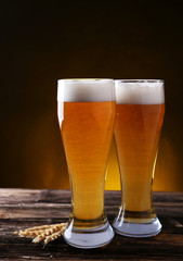 Two glass of beer on brown wooden background
