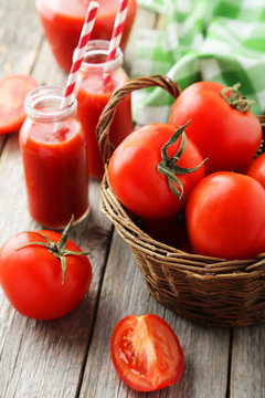 Fresh red tomatoes in basket and juice in bottles 