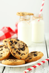 Two bottles of milk with striped straws and cookies 