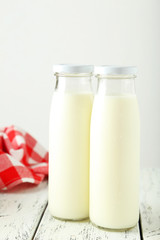 Two bottles of milk on white wooden background