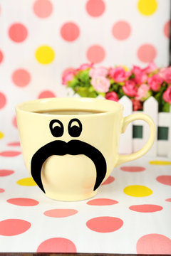 Yellow cup with paper mustache on colorful background