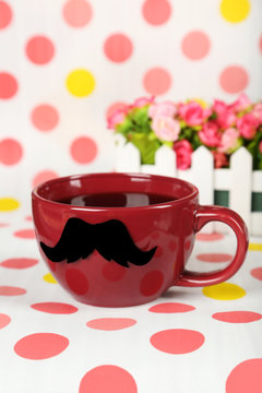 Red cup with paper mustache on colorful background