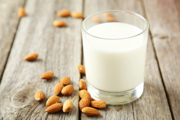 Glass of milk with almonds on grey wooden background