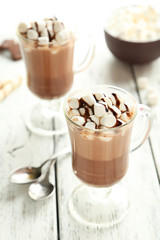 Glasses of hot chocolate with marshmallows on white wooden backg