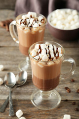 Glasses of hot chocolate with marshmallows on grey wooden backgr