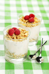 Muesli with yogurt and raspberries in a glass on napkin