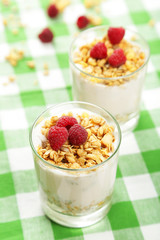 Muesli with yogurt and raspberries in a glass on napkin