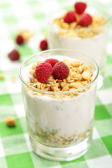 Muesli with yogurt and raspberries in a glass on napkin