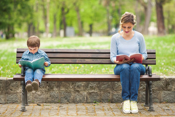 Little boy and his mother sitting on a park bench 